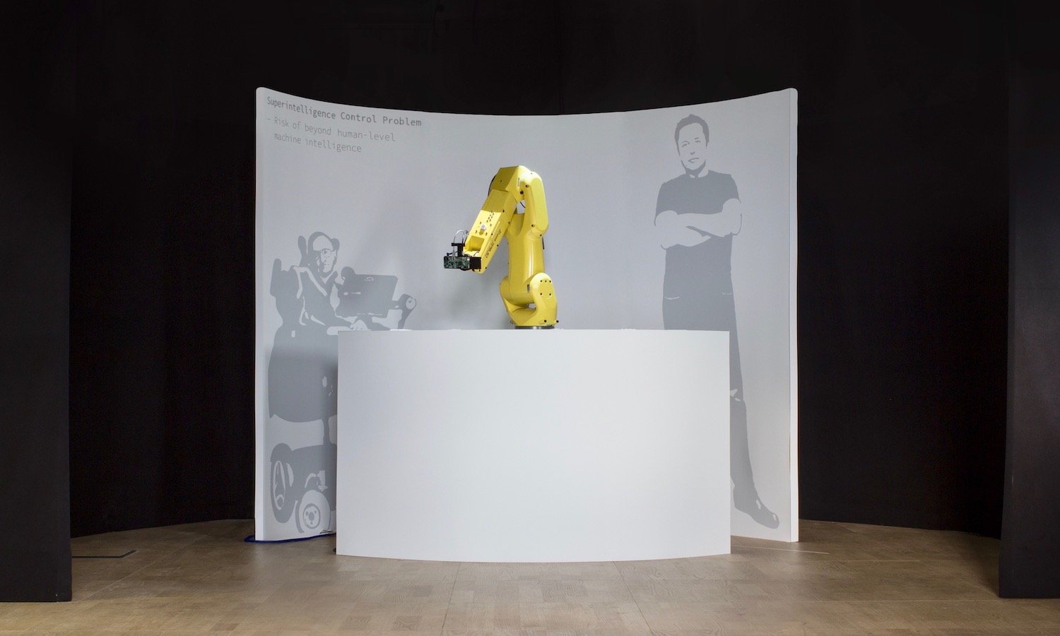 The result: Completed exhibition with a desk in the front, robot in the center, backdrop with silhouettes, and exits on the sides.